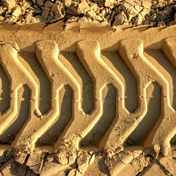 Excavator track marks pressed into sand on a Platinum plant hire site
